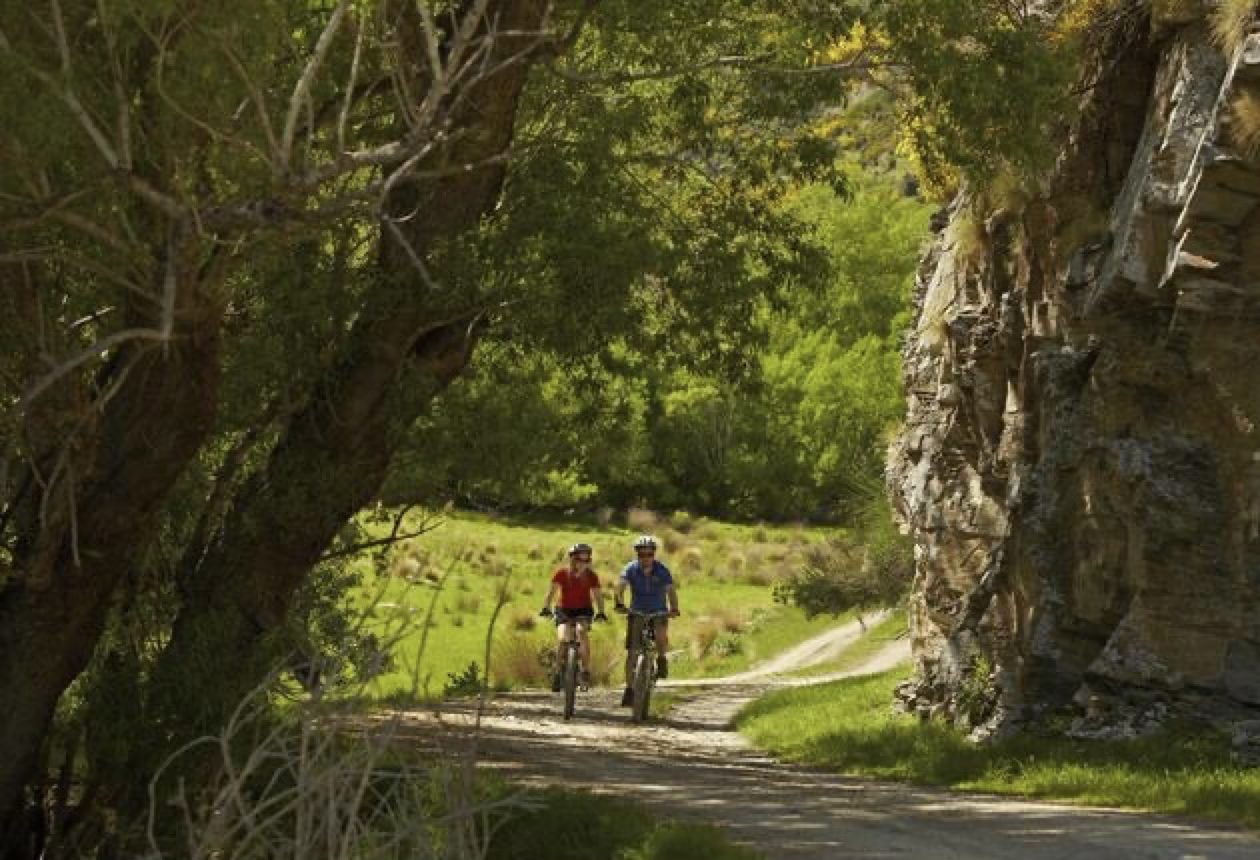 Riders passing a rock bluff on a gravel path